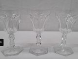 three clear wine glasses sitting on top of a white table