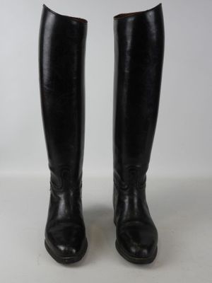 a pair of black leather riding boots on a white surface