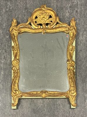 un miroir au cadre doré ouvragé posé sur une surface grise