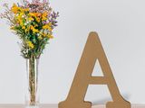 a vase of flowers and a wooden letter on a dresser