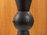 a black vase sitting on a table with a wooden wall in the background