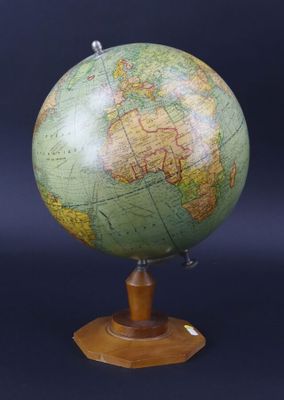 un globe vert posé sur un socle en bois, sur fond noir