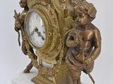a gold clock with angels on it on a marble base