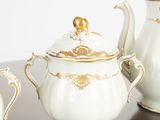 three white and gold teapots sitting on a table