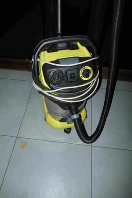un aspirateur jaune et noir posé sur un sol carrelé