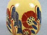 un vase jaune orné de fleurs bleues et rouges