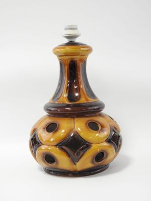 un vase brun et noir posé sur une surface blanche