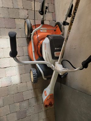 une tondeuse à gazon orange et blanche posée sur un mur de briques