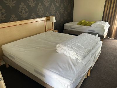 deux lits dans la chambre, recouverts de draps blancs