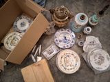 une boîte remplie d'assiettes en porcelaine et d'autres objets, posée par terre