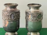 two silver vases sitting next to each other on a green table