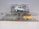 three small toy cars in clear boxes on a white surface