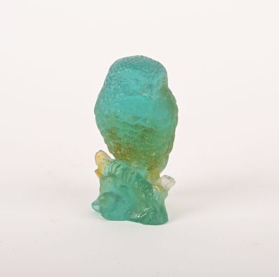 une petite figurine en verre représentant un oiseau perché sur une branche