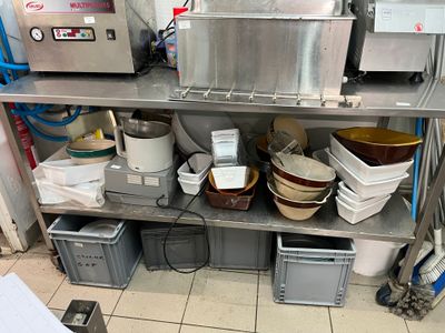 de nombreux bols et casseroles posés sur une étagère métallique dans une cuisine