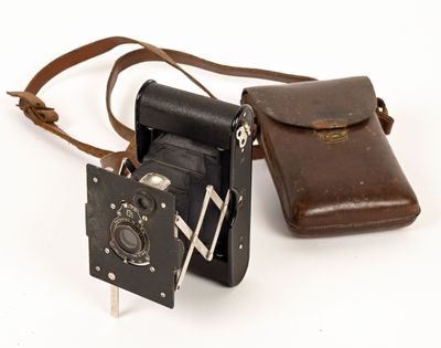 un vieil appareil photo dans un étui en cuir, posé sur une surface blanche