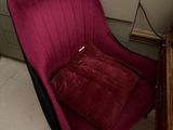 a red chair that is sitting in front of a book shelf
