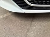the front end of a white car parked in a parking lot