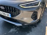 the front end of a silver car parked on the side of the road