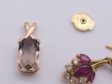 two pairs of earrings and a pendant are shown on a white surface