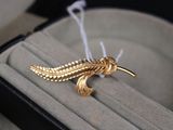 une broche en forme d'oiseau en or posée sur une bague