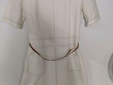 the white dress is hanging on a hanger on the wall