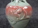 un vase vert orné d'un motif rouge et blanc