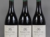 three bottles of red wine are lined up on a table