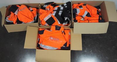 des cartons contenant des vêtements orange et noirs posés sur un sol noir