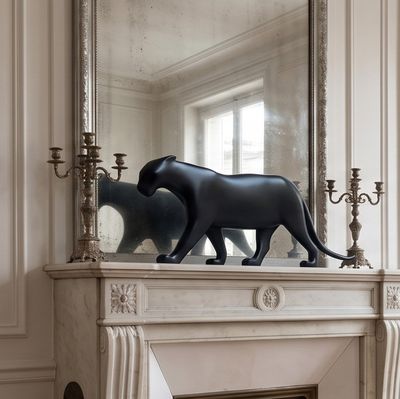 a statue of a cat on a mantle in front of a mirror