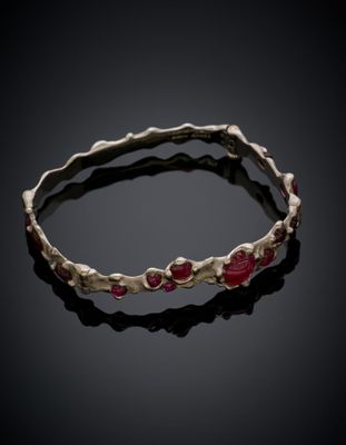 a close up of a bracelet with red stones on a black surface