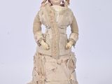 an antique doll of a woman in a dress and hat