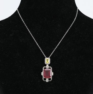 un collier en argent avec un pendentif rouge et jaune sur un mannequin noir