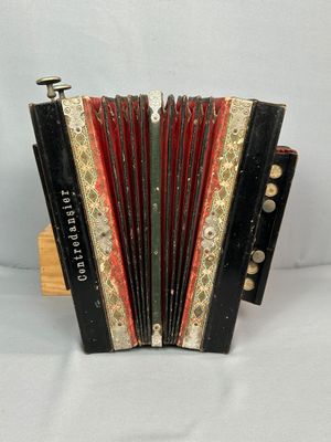 un vieil accordéon noir et rouge posé sur un support en bois