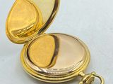 a gold pocket watch sitting on a table next to a wooden box