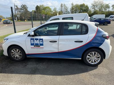 a white and blue car parked in a parking lot next to a fence
