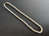 a close up of a white pearl necklace on a black surface