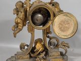 a gold clock with angels and cherensils on it