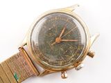 a gold watch with a green face on a white surface