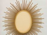 a close up of a gold sunburst on a white wall