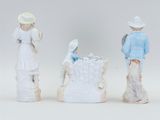 three figurines of children and a baby in a crib