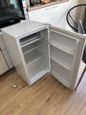 an open refrigerator sitting in a kitchen next to a dining room table