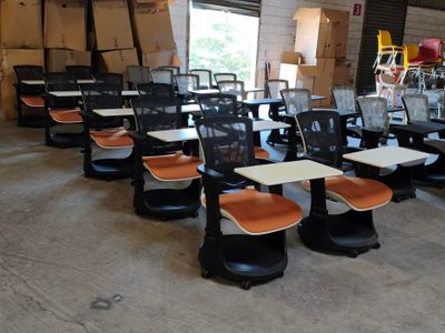 de nombreuses chaises et tables dans un entrepôt rempli de cartons