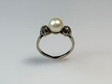 a close up of a pearl ring on a white surface