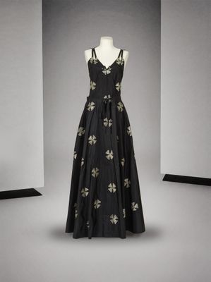 robe de soirée noire ornée de fleurs dorées, présentée sur un mannequin, avec un décolleté