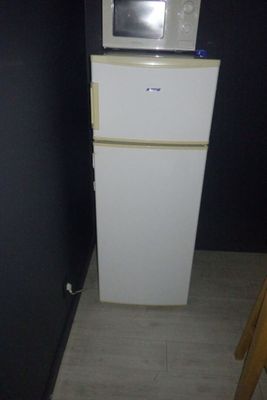 un petit réfrigérateur blanc surmonté d'un micro-ondes