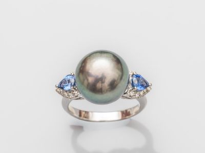 une bague ornée d'une perle noire et d'un saphir bleu sur fond blanc