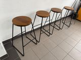 three wooden stools sitting on top of a tiled floor next to a wall