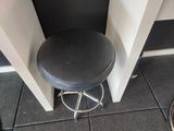 a black stool with a black seat in a corner