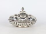 an antique silverplated sugar dish with a lid on a white background