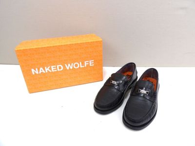 une paire de mocassins noirs posés sur une surface blanche, à côté d'une boîte